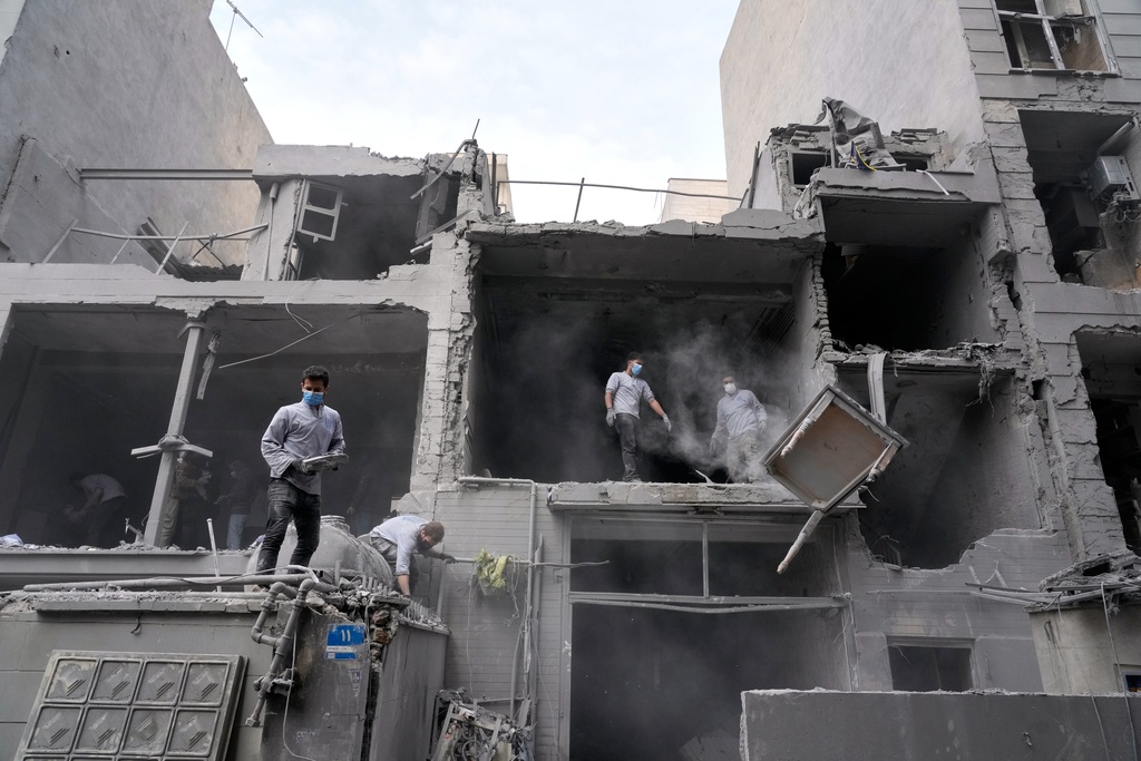 Volunteers clean debris from a residential building damaged when a nearby police station was hit Friday in a U.S.-Israeli strike in Tehran, Iran, Sunday, March 15, 2026. (AP Photo/Vahid Salemi)