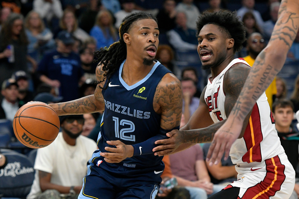 Memphis Grizzlies guard Ja Morant (12) handles the ball against Miami Heat guard Davion Mitchell (45) in the first half of an NBA basketball game Friday, Oct. 24, 2025, in Memphis, Tenn. (AP Photo/Brandon Dill)