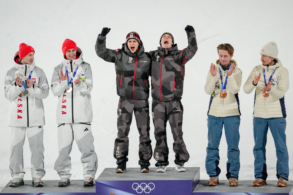 Gold medalists Stephan Embacher and Jan Hoerl, of Austria, celebrate on the podium, with silver medalists Pawel Wasek and Kacper Tomasiak, of Poland, and bronze medalists Kristoffer Eriksen Sundal and Johann Andre Forfang, of Norway, after the ski jumping men's super team competition at the 2026 Winter Olympics, in Predazzo, Italy, Monday, Feb. 16, 2026. (AP Photo/Matthias Schrader)