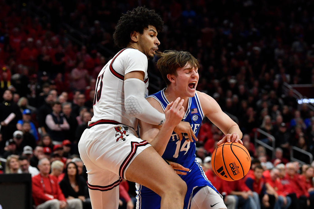 Duke guard Nikolas Khamenia (14) attempts to get past Louisville forward Sananda Fru (13) during the first half of an NCAA college basketball game in Louisville, Ky., Tuesday, Jan. 6, 2026. (AP Photo/Timothy D. Easley)