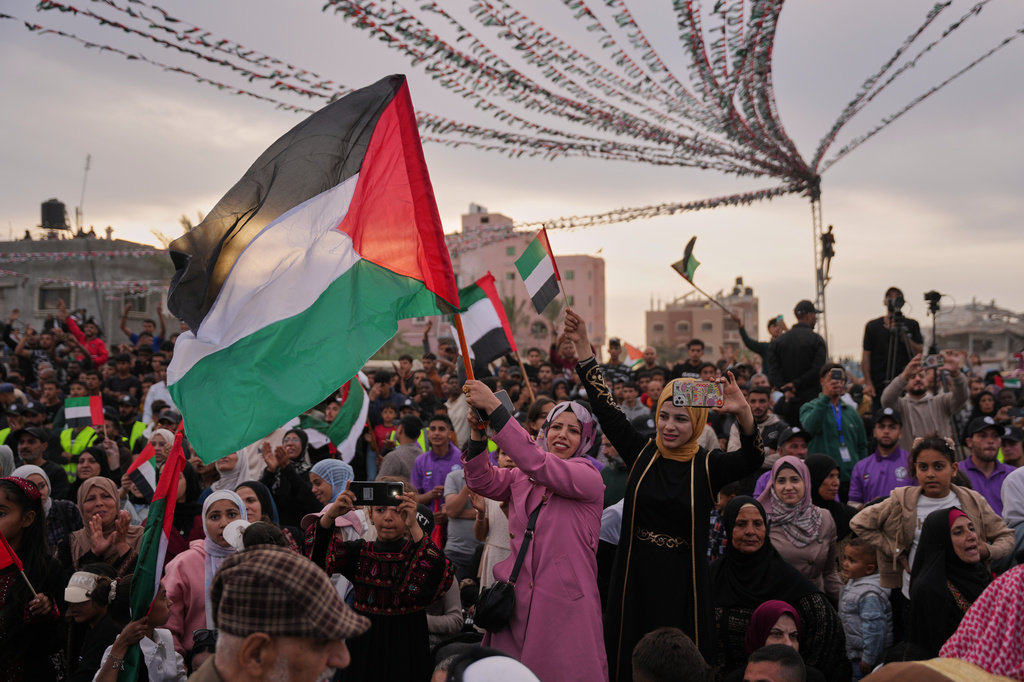 A woman waves a Palestinian flag as she watches a mass wedding ceremony in Deir al-Balah, central Gaza Strip, Friday, April 24, 2026. (AP Photo/Abdel Kareem Hana)