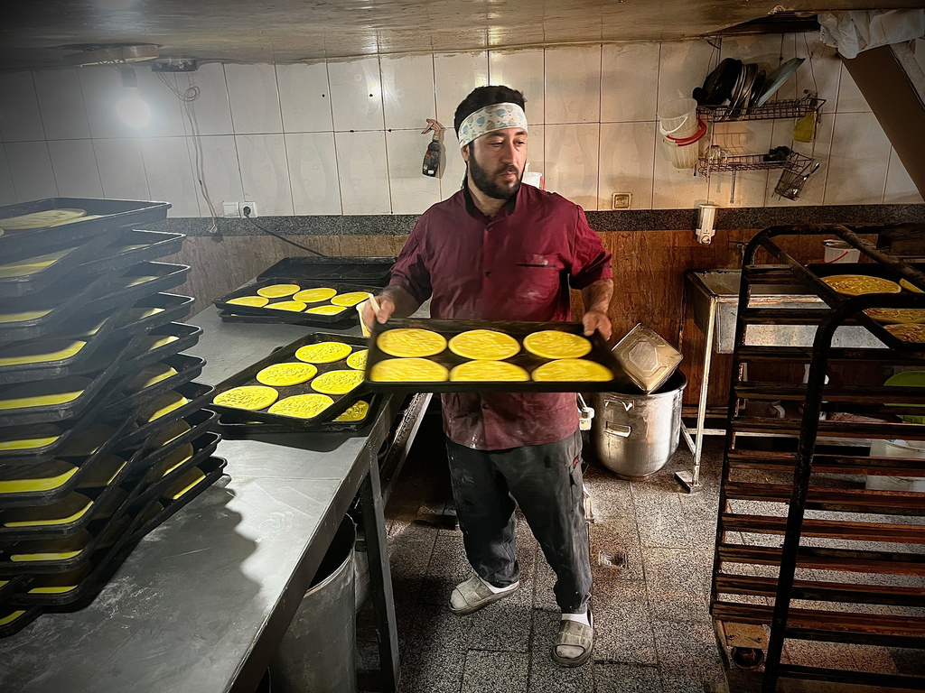 A baker pulls a rack of freshly baked local bread in a roadside bakery on Road 16 in Bostanabad, Iran, Thursday, April 9, 2026. (AP Photo/Francisco Seco)