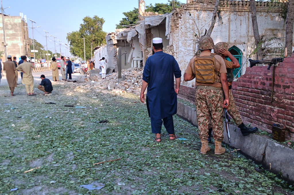 In this photo taken with a smartphone, army soldiers and local residents gather at the site of a powerful bomb exploded at a mosque in Kohat, in northwestern Pakistan, Friday, Sept. 18, 2026. (AP Photo/B.S. Gillani)
