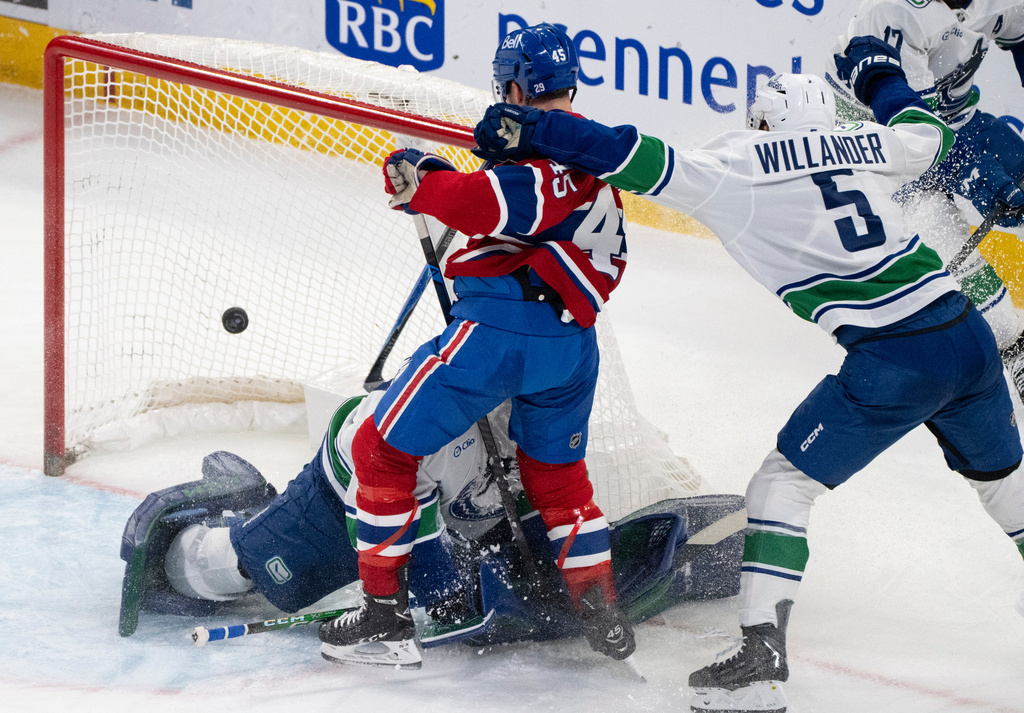 Montreal Canadiens' Alexandre Carrier (45) scores against Vancouver Canucks goaltender Nikita Tolopilo, bottom left, as Canucks' Tom Willander (5) defends during second-period NHL hockey game action in Montreal, Monday, Jan. 12, 2026. (Christinne Muschi/The Canadian Press via AP)