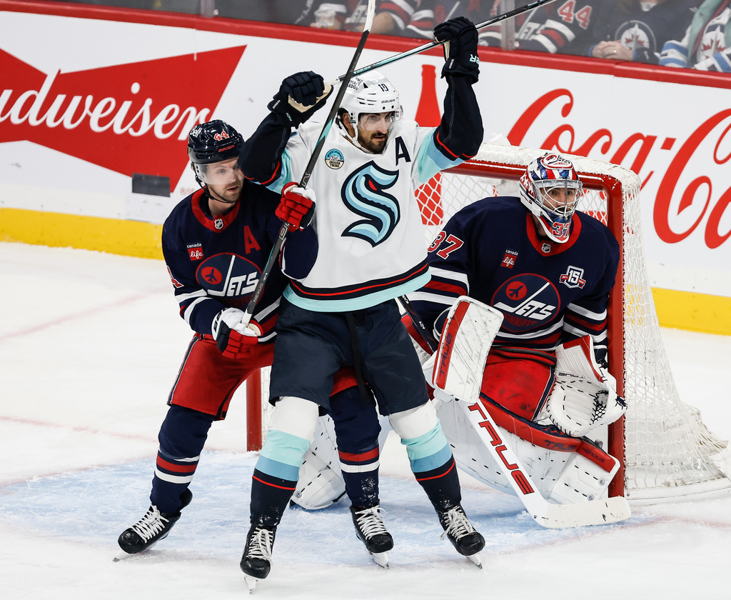 Winnipeg Jets' Josh Morrissey (44) defends against Seattle Kraken's Matty Beniers (10) in front of goaltender Connor Hellebuyck (37) during first period NHL action in Winnipeg on Thursday, Oct. 23, 2025. (John Woods/The Canadian Press via AP)