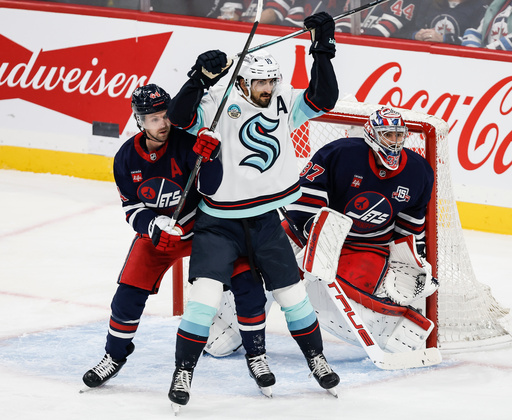 Winnipeg Jets' Josh Morrissey (44) defends against Seattle Kraken's Matty Beniers (10) in front of goaltender Connor Hellebuyck (37) during first period NHL action in Winnipeg on Thursday, Oct. 23, 2025. (John Woods/The Canadian Press via AP) Winnipeg Jets' Josh Morrissey (44) defends against Seattle Kraken's Matty Beniers (10) in front of goaltender Connor Hellebuyck (37) during first period NHL action in Winnipeg on Thursday, Oct. 23, 2025. (John Woods/The Canadian Press via AP)