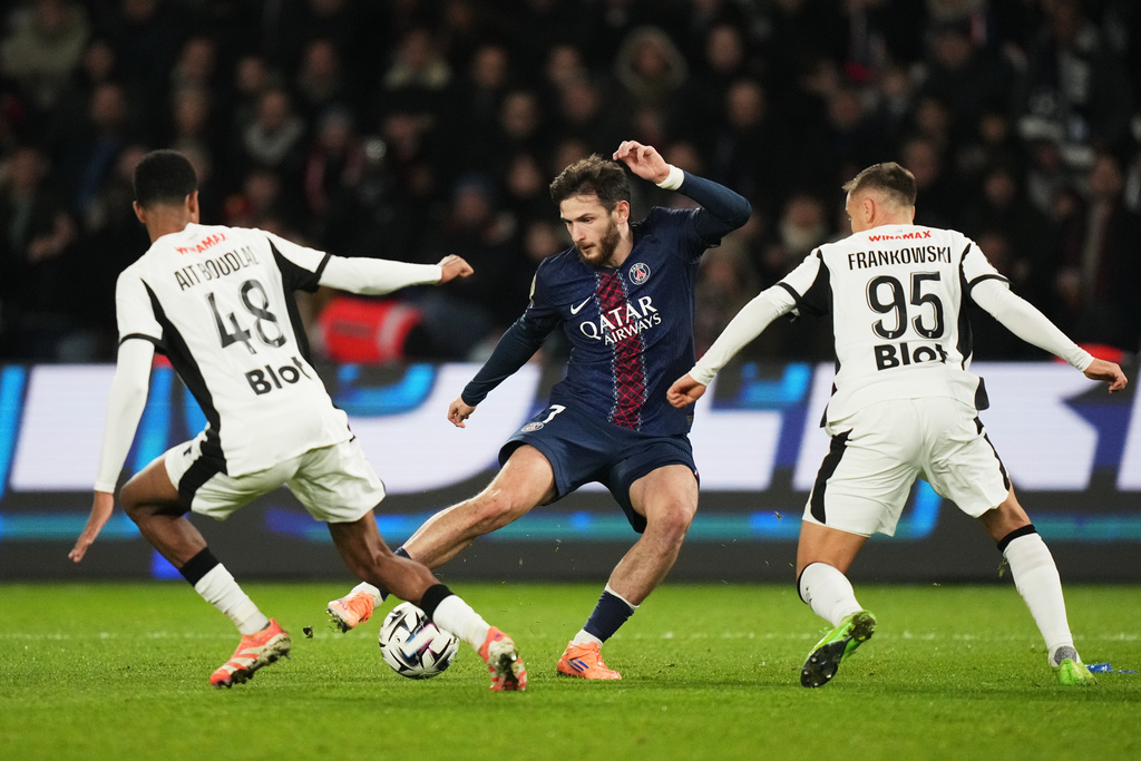 PSG's Khvicha Kvaratskhelia, center, challenges for the ball with Rennes' Abdelhamid Ait Boudlal, left, and Rennes' Przemyslaw Frankowski, right, during the French League One soccer match between Paris and Rennes in Paris, France, Saturday, Dec. 6, 2025. (AP Photo/Thibault Camus)