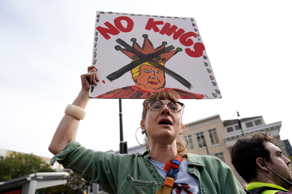 A demonstrator carries a sign as they rally at the 14th and U street corridor before marching to the national Mall during a No Kings protest in Washington, Saturday, Oct. 18, 2025. (AP Photo/Jose Luis Magana)