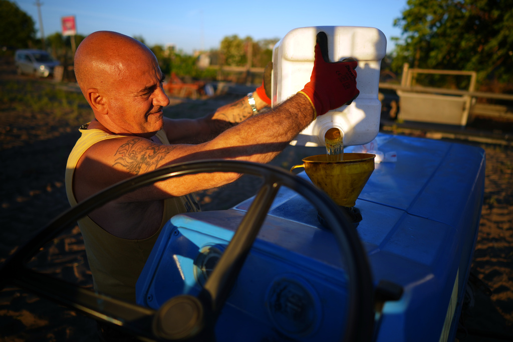 Enzo Garbaglia refuels his tractor while harvesting potatoes on his farm in Fiumicino, Italy, on Friday, June 12, 2026. (AP Photo/Andrew Medichini)