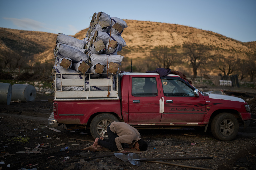 A Muslim worker prays next to a vehicle loaded with sacks of charcoal at a traditional production site in Sarkand, Iraq, Thursday, March 12, 2026. (AP Photo/Leo Correa)