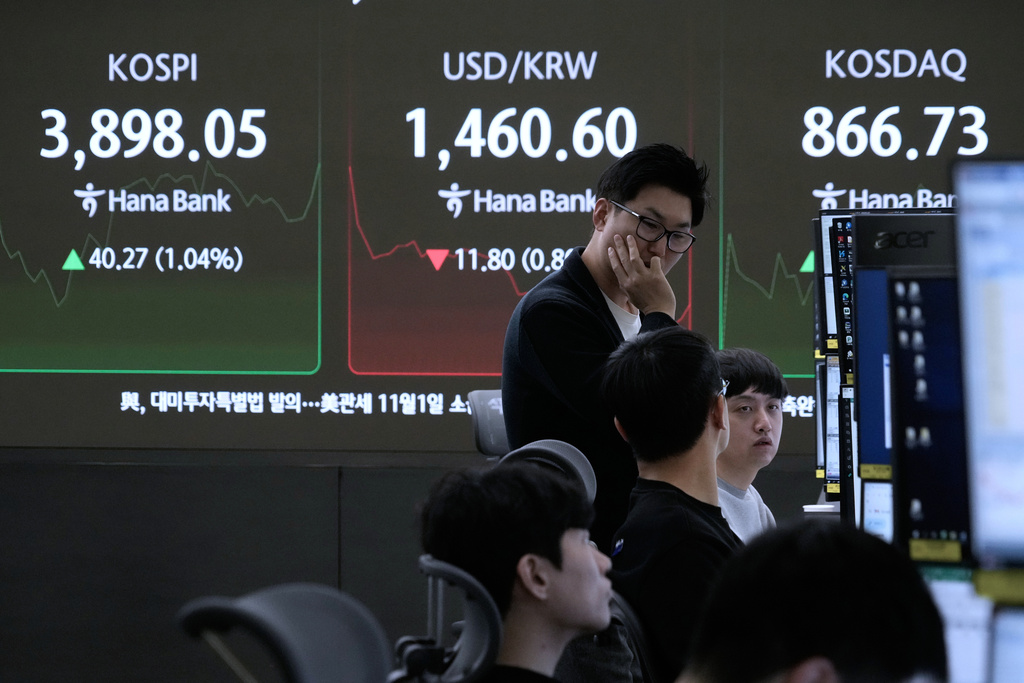 Currency traders work near a screen showing the Korea Composite Stock Price Index (KOSPI), top left, and the foreign exchange rate between U.S. dollar and South Korean won, top center, at the foreign exchange dealing room of the Hana Bank headquarters in Seoul, South Korea, Wednesday, Nov. 26, 2025. (AP Photo/Ahn Young-joon)
