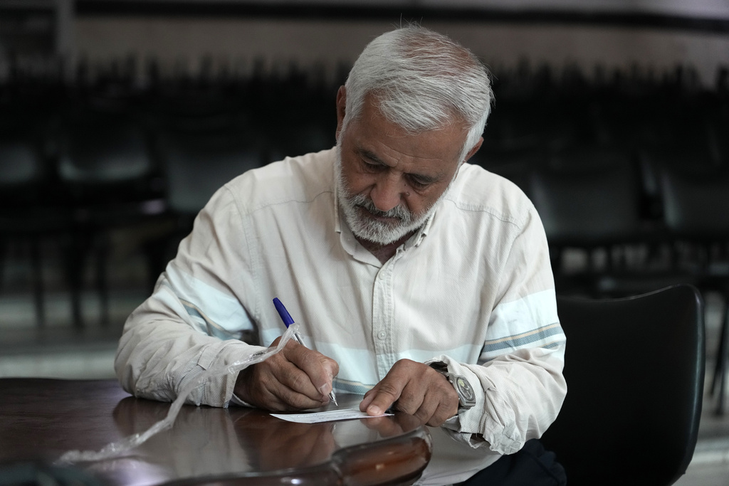 An Iranian man fills out his ballot for the presidential runoff election at a polling station in Tehran, Iran, Friday, July 5, 2024. Iranians began voting Friday in a runoff election to replace the late President Ebrahim Raisi, killed in a helicopter crash last month, as public apathy has become pervasive in the Islamic Republic after years of economic woes, mass protests and tensions in the Middle East. (AP Photo/Vahid Salemi)