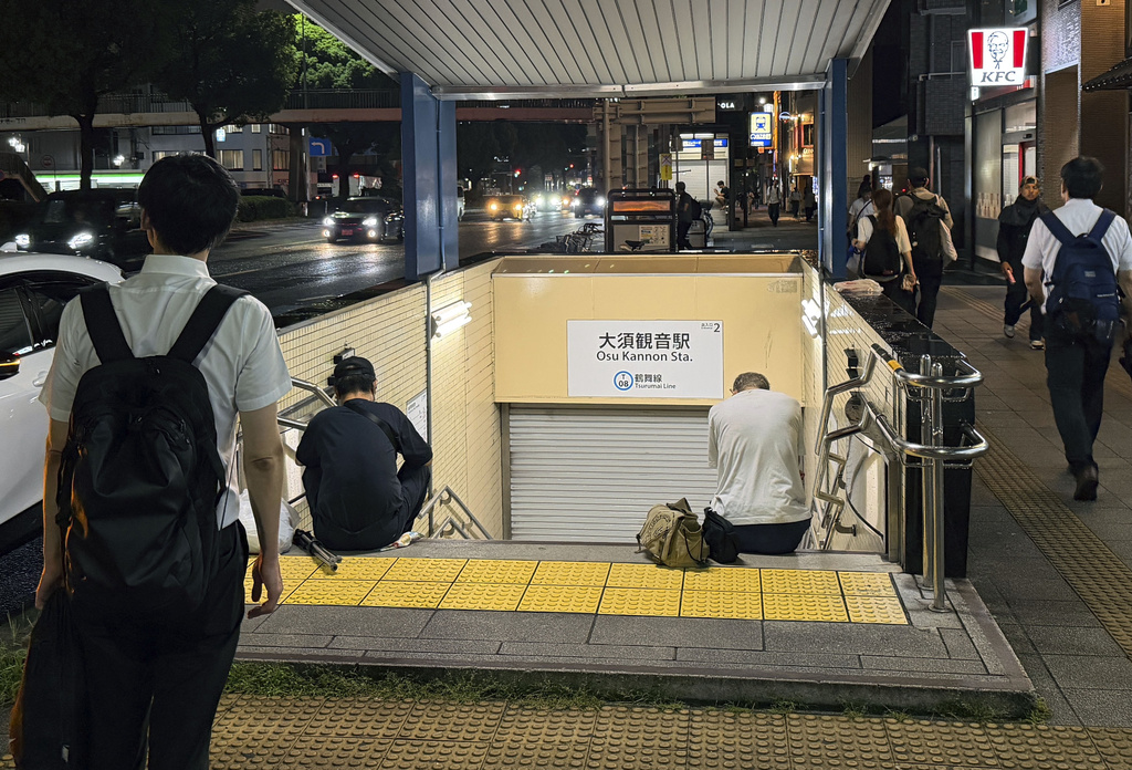 People sit in front of a shuttered entrance to a subway station after all train services were suspended due to a heavy rain in Nagoya, central Japan Tuesday, Sept. 8, 2026. (Shigeyuki Inakuma/Kyodo News via AP)