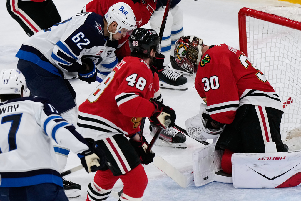 Chicago Blackhawks goaltender Spencer Knight (30) saves a shot by Winnipeg Jets right wing Nino Niederreiter (62) during the first period of an NHL hockey game in Chicago, Monday, Jan. 19, 2026. (AP Photo/Nam Y. Huh)