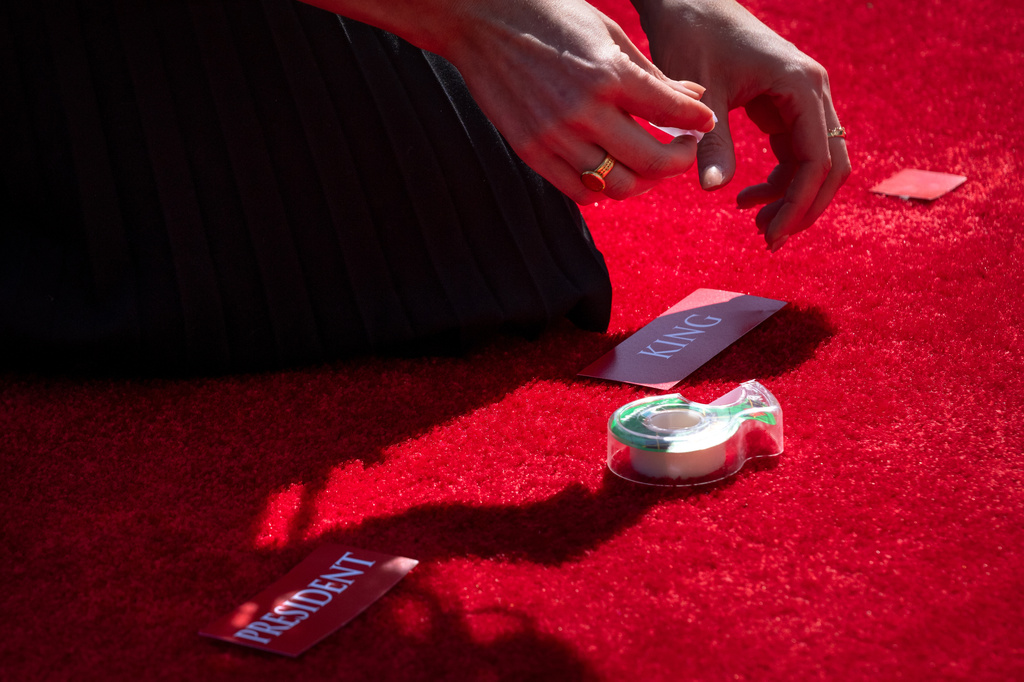A staff member places tags for Britain's King Charles III and President Donald Trump on the red carpet before the arrival of the Britain's King Charles III and Queen Camilla at the White House, Monday, April 27, 2026, in Washington. (AP Photo/Mark Schiefelbein)