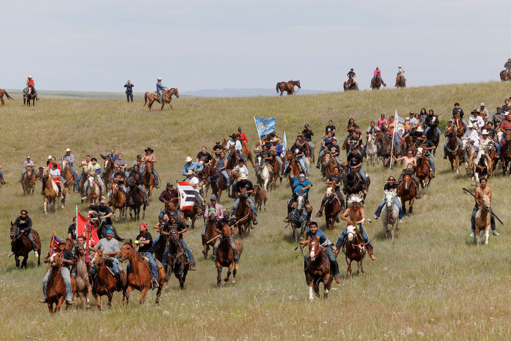Riders charge toward spectators during festivities to commemorate the 150th anniversary of the Battle of the Little Bighorn in Crow Agency, Mont., on Thursday, June 25, 2026. (AP Photo/Tailyr Irvine)