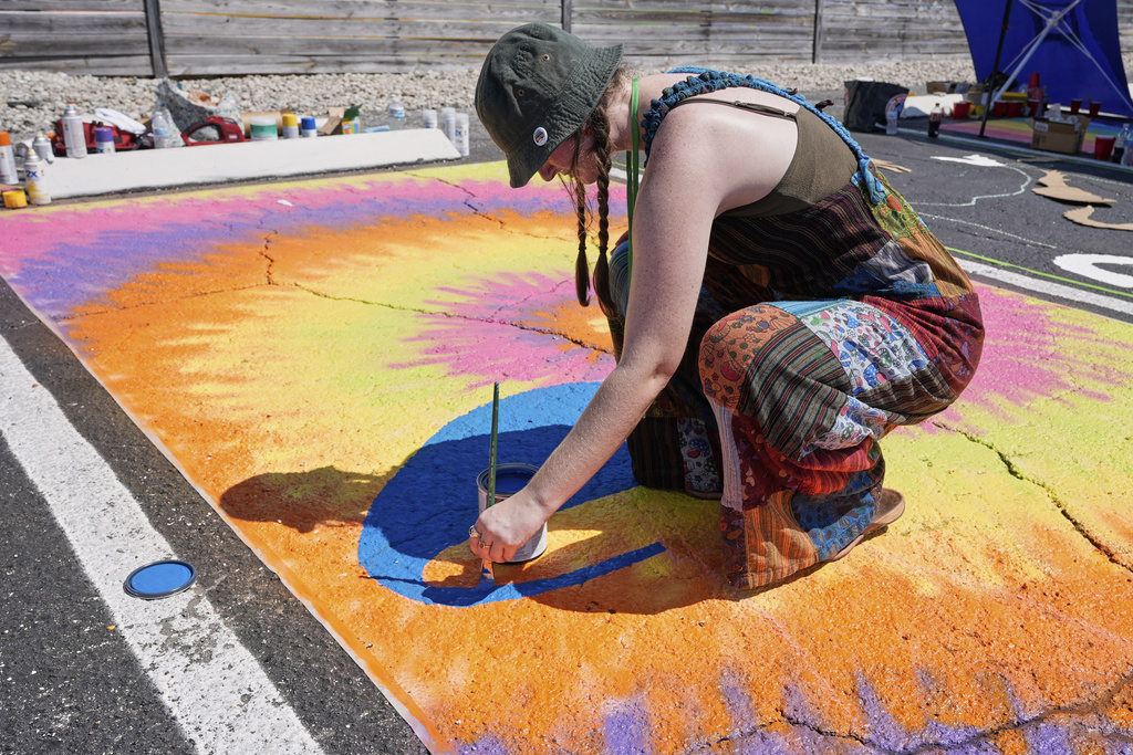 Courtney Cochrane paints a parking space at a local restaurant to support the LBGTQ+ community and to protest state mandates on crosswalk art Monday, Sept. 15, 2025, in Orlando, Fla. (AP Photo/John Raoux)