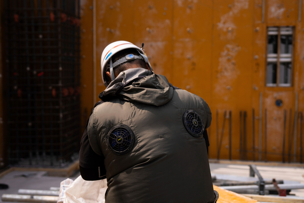 FILE - An employee works at a construction site wearing a fan-equipped vest in Tokyo, July 9, 2025. (AP Photo/Louise Delmotte, File)