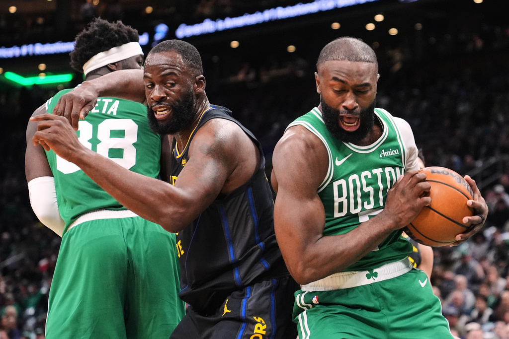 Boston Celtics guard Jaylen Brown, right, grabs a rebound against Golden State Warriors forward Draymond Green (23) during the first half of an NBA basketball game, Wednesday, March 18, 2026, in Boston. (AP Photo/Charles Krupa)