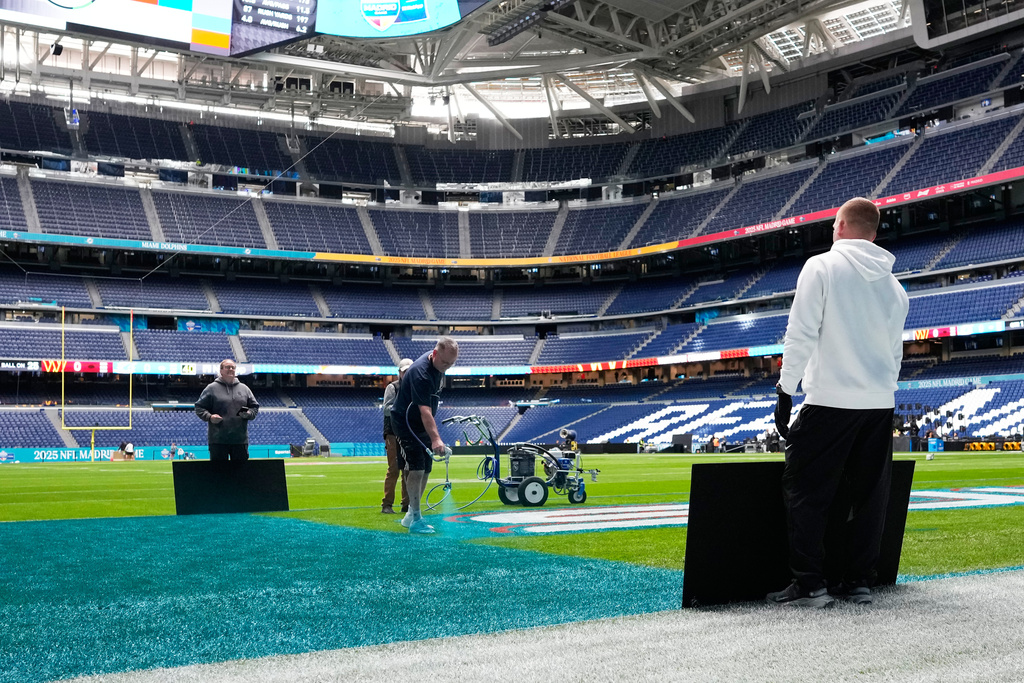 Workers prepare the field at the Santiago Bernabeu stadium ahead of an NFL game between the Miami Dolphins and Washington Commanders in Madrid, Spain, Friday, Nov. 14, 2025. (AP Photo/Steve Luciano)