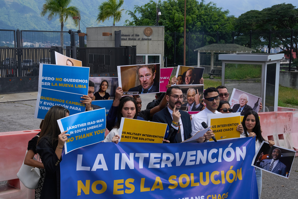 Gabriel Cabrera, president of the Venezuelan Youth Center for Democracy, gives a statement outside of the U.S. embassy with members of the organization holding signs that read in Spanish "Intervention is not the solution," in reference to U.S. warships operating in the Caribbean, in Caracas, Venezuela, Monday, Oct. 27, 2025. (AP Photo/Ariana Cubillos)