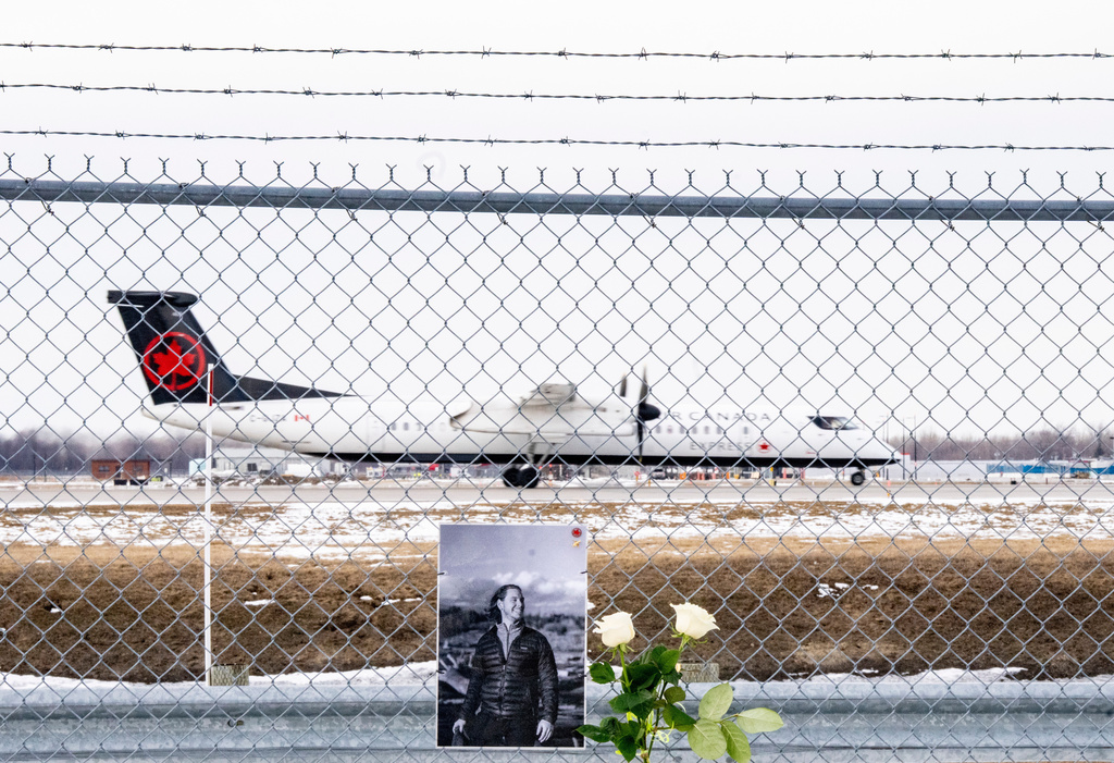 An Air Canada Express plane takes off in Montreal, on Wednesday, March 25, 2026, wldbehind a memorial for Air Canada Jazz pilot Antoine Forest, who died when his plane collided with an emergency vehicle at New York's LaGuardia Airport. (Christinne Muschi/The Canadian Press via AP)
