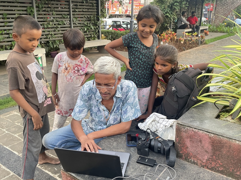 Associated Press photographer Rajanish Kakade works, watched by children in Mumbai, India, Aug. 23, 2023. (AP Photo)