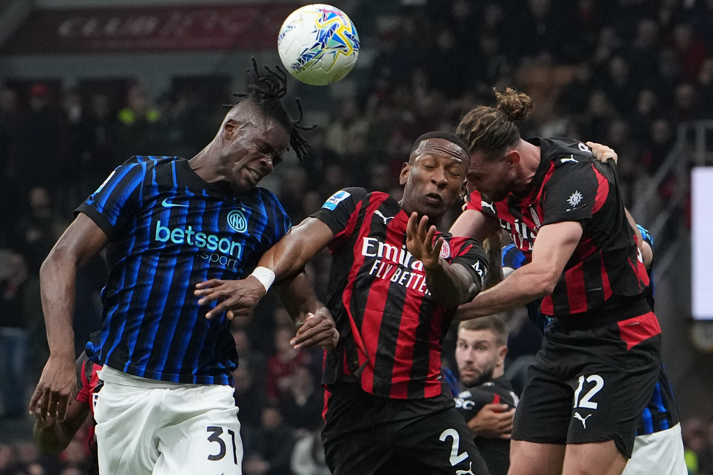 Inter Milan's Yann Bisseck, left, AC Milan's Pervis Estupinan, center, and Adrien Rabiot jump for the ball during the Serie A soccer match between AC Milan and Inter Milan, in Milan, Italy, Sunday, March 8, 2026. (AP Photo/Antonio Calanni)