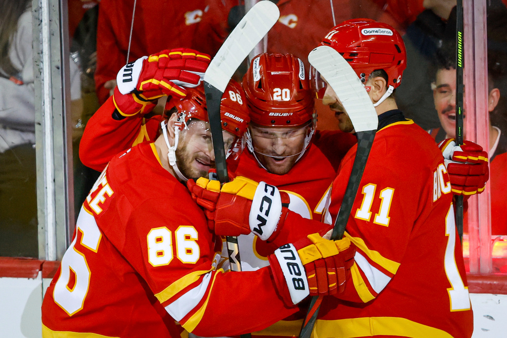 Calgary Flames' Joel Farabee, left, celebrates his goal with teammates Blake Coleman, center, and Mikael Backlund during the second period of an NHL hockey game against the Florida Panthers in Calgary on Friday, March 20, 2026. (Jeff McIntosh/The Canadian Press via AP)