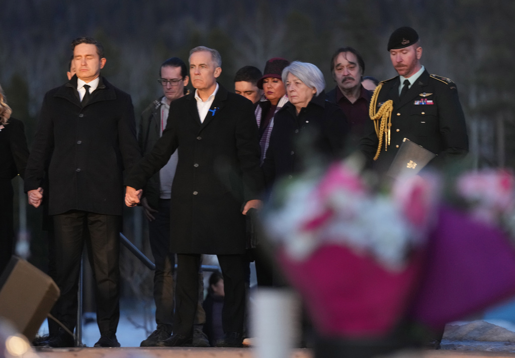 From left to right, Leader of the Official Opposition of Canada Pierre Poilievre, Prime Minister Mark Carney and Governor General of Canada, Mary Simon join hands while attending a vigil for the victims of a mass shooting, in Tumbler Ridge, B.C., Friday, Feb. 13, 2026. (Christinne Muschi/The Canadian Press via AP)