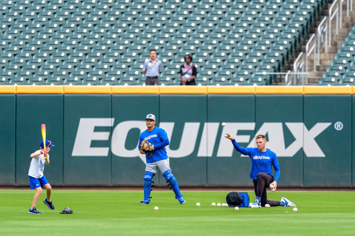 FILE - Los Angeles Dodgers first baseman Freddie Freeman, right, and third baseman Enrique Hernández, center, conduct hitting practice with Freeman's son, Charlie Freeman, left, in center field prior to a baseball game against the Atlanta Braves, Sept. 16, 2024, in Atlanta. (AP Photo/Jason Allen, File) FILE - Los Angeles Dodgers first baseman Freddie Freeman, right, and third baseman Enrique Hernández, center, conduct hitting practice with Freeman's son, Charlie Freeman, left, in center field prior to a baseball game against the Atlanta Braves, Sept. 16, 2024, in Atlanta. (AP Photo/Jason Allen, File)