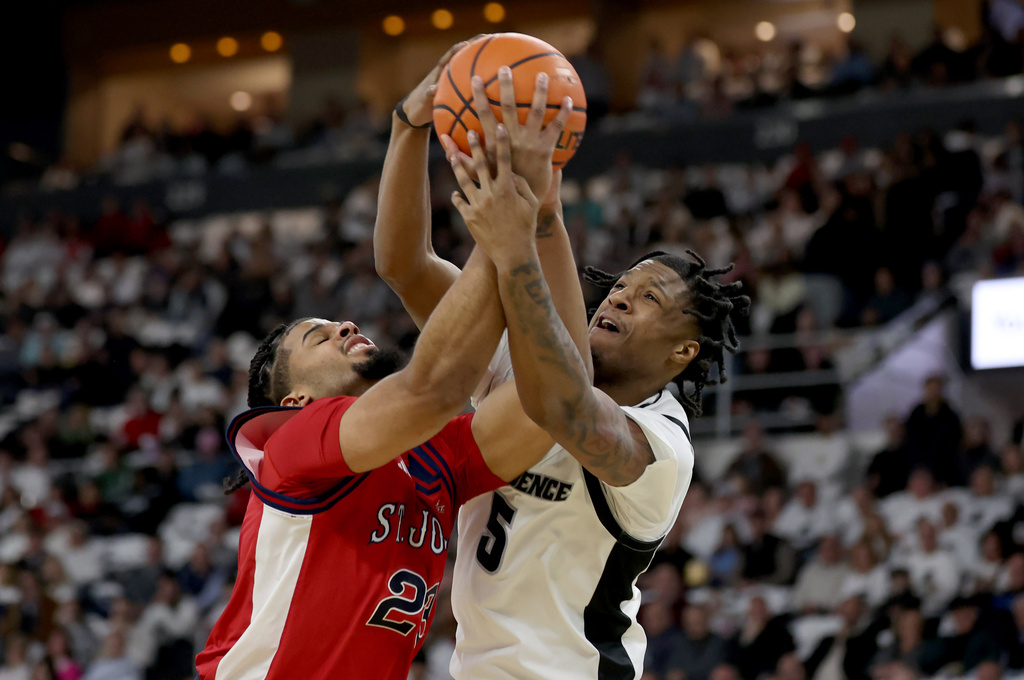 Providence forward Jamier Jones (5) fouls St. John's forward Bryce Hopkins (23) under the net during the first half of an NCAA college basketball game, Saturday, Feb. 14, 2026, in Providence, R.I. (AP Photo/Mark Stockwell)