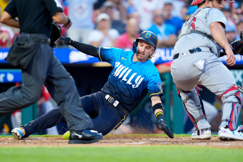 Philadelphia Phillies' Bryson Stott, center, slides into home on the double by Brandon Marsh during the second inning of a baseball game against the St. Louis Cardinals, Friday, Aug. 21, 2026, in Philadelphia. (AP Photo/Chris Szagola)