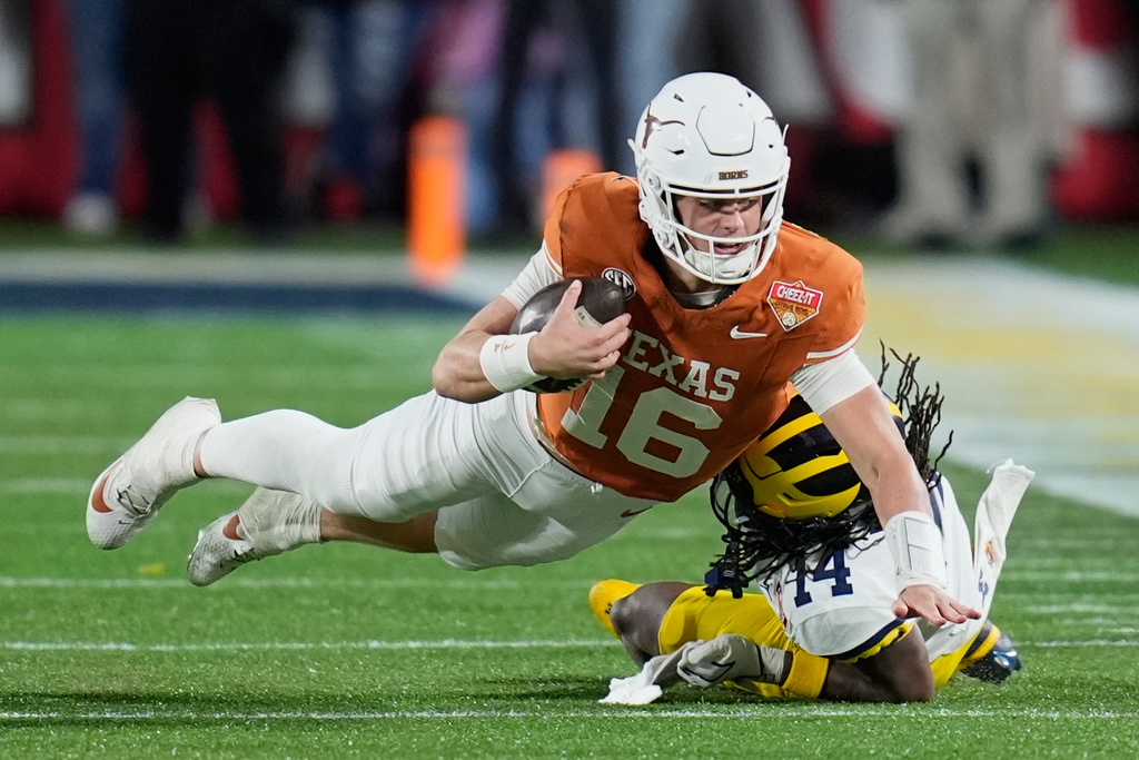 Texas quarterback Arch Manning (16) dives as he is tackled by Michigan defensive back Jordan Young during the second half of the Citrus Bowl NCAA college football game, Wednesday, Dec. 31, 2025, in Orlando, Fla. (AP Photo/John Raoux)