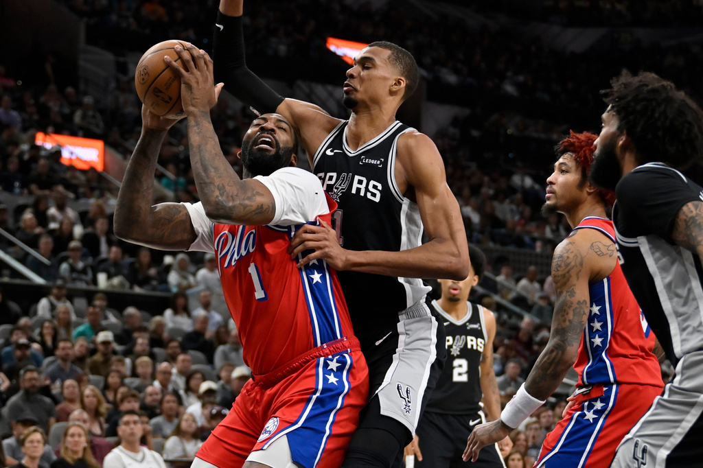 Philadelphia 76ers center Andre Drummond, left, tangles with San Antonio Spurs center Victor Wembanyama during the first half of an NBA basketball game, Monday, April 6, 2026, in San Antonio. (AP Photo/Darren Abate)