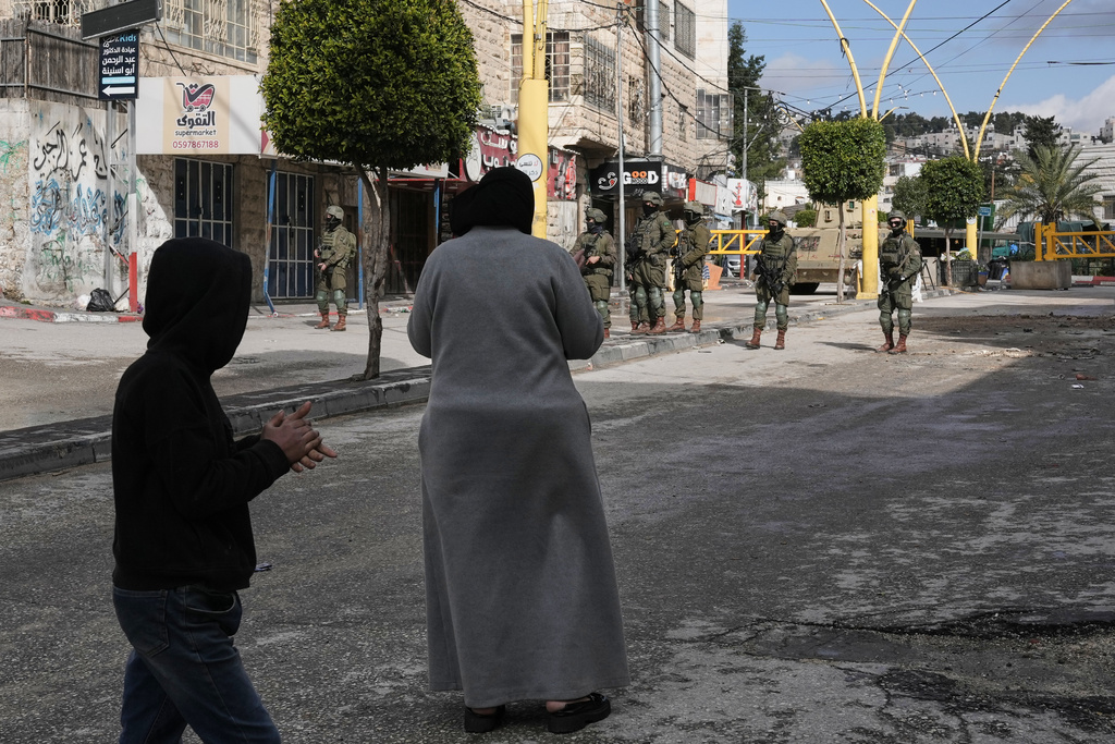 Israeli soldiers take up positions during an army raid in the West Bank city of Hebron Monday, Jan. 19, 2026. (AP Photo/Mahmoud Illean)