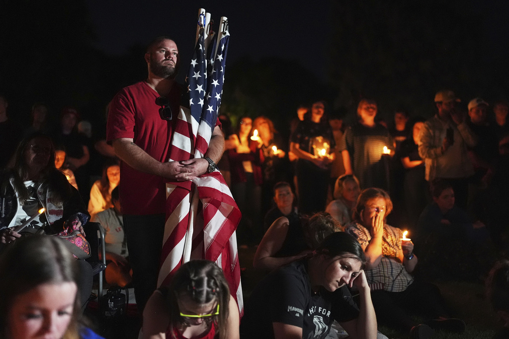 Ryan Shaw holds American flags during a vigil for Charlie Kirk on Friday, Sept. 12, 2025, in Provo, Utah. (AP Photo/Lindsey Wasson)