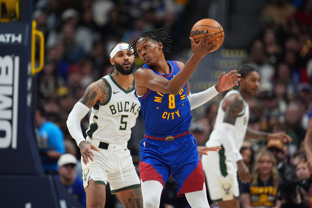 Denver Nuggets guard Peyton Watson, front, fields a pass as Milwaukee Bucks guard Gary Trent Jr. defends in the first half of an NBA basketball game, Sunday, Jan. 11, 2026, in Denver. (AP Photo/David Zalubowski)