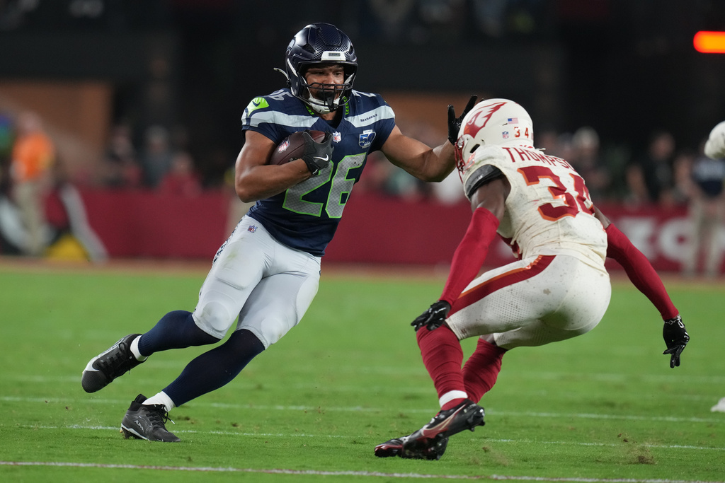 Seattle Seahawks running back Zach Charbonnet (26) runs with the ball as Arizona Cardinals safety Jalen Thompson (34) defends during the first half of an NFL football game Thursday, Sept. 25, 2025, in Glendale, Ariz. (AP Photo/Rick Scuteri)