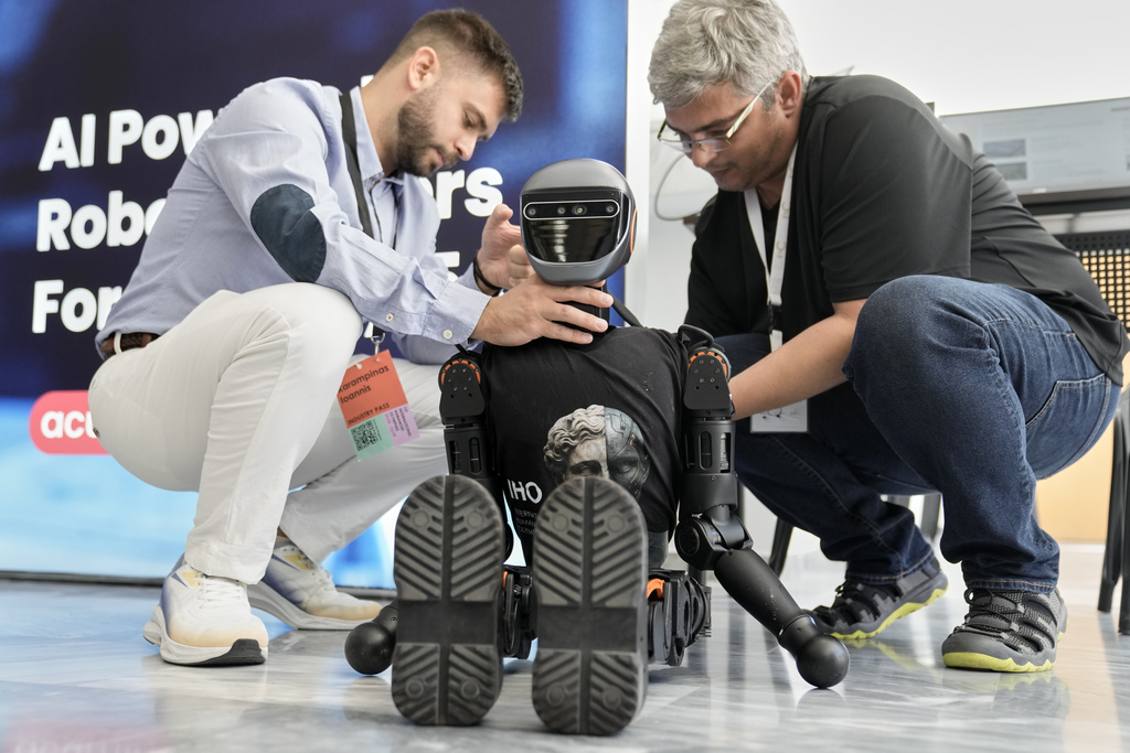 Spiros Makris, right, and Ioannis Karampinas technicians of Acumino replace a battery at the Booster T1 robot during the first International Humanoid Olympiad at the Olympic Academy, in ancient Olympia, Greece, Monday, Sept. 1, 2025. (AP Photo/Thanassis Stavrakis)
