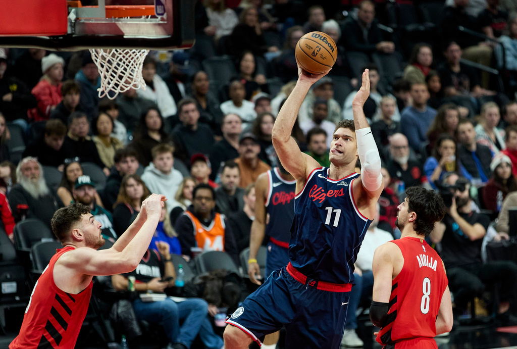 Los Angeles Clippers center Brook Lopez, center, shoots between Portland Trail Blazers center Donovan Clingan, left, and forward Deni Avdija during the second half of an NBA basketball game in Portland, Ore., Friday, Dec. 26, 2025. (AP Photo/Craig Mitchelldyer)
