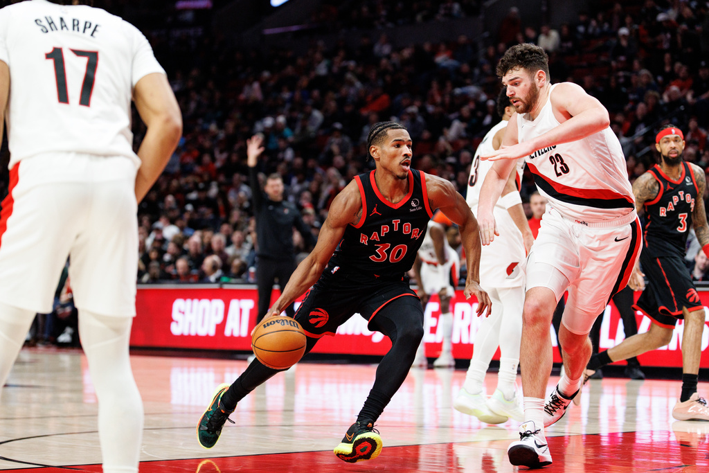 Toronto Raptors guard Ochai Agbaji, center, drives to the basket against Portland Trail Blazers center Donovan Clingan, front right, during the second half of an NBA basketball game Friday, Jan. 23, 2026, in Portland, Ore. (AP Photo/Howard Lao)