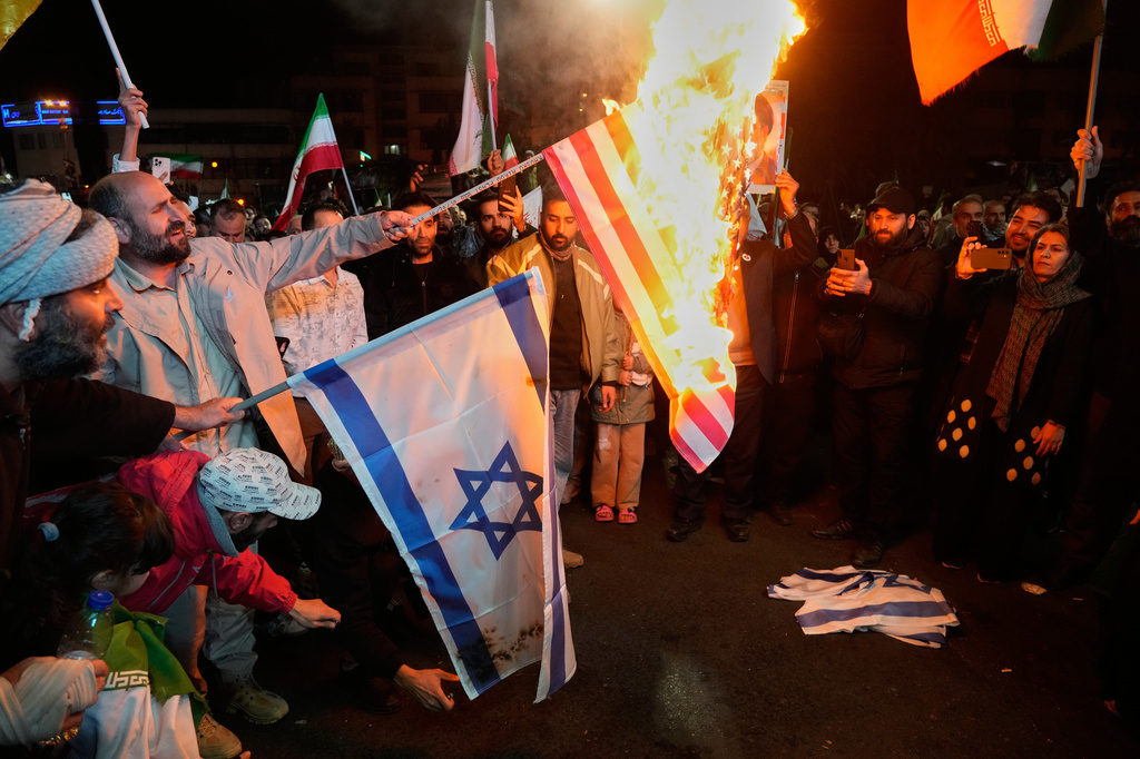 Iranian pro-government demonstrators burn the U.S. and Israeli flags during a gathering after announcement of a two-week ceasefire in the war with the United States and Israel, at the Enqelab-e-Eslami, or Islamic Revolution, Square, in Tehran, Iran, Wednesday, April 8, 2026. (AP Photo/Vahid Salemi)