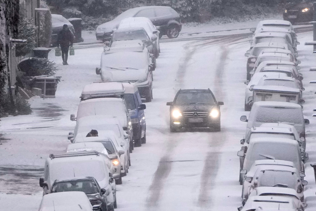 A car drives carefully on a snowy street when people facing a cold wave bringing winter weather with snow and ice to the industrial Ruhr area in Gelsenkirchen, Germany, Wednesday, Jan. 7, 2026. (AP Photo/Martin Meissner)