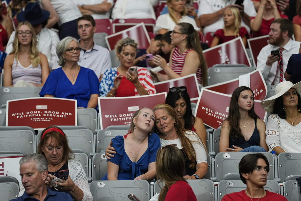 People sit inside before the start of a memorial for conservative activist Charlie Kirk, Sunday, Sept. 21, 2025, at State Farm Stadium in Glendale, Ariz. (AP Photo/John Locher)
