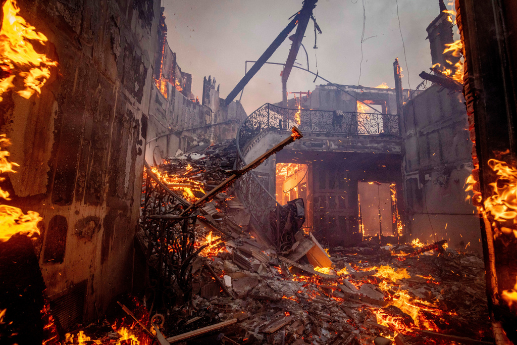 FILE - The Palisades Fire burns a residence in the Pacific Palisades neighborhood of Los Angeles, Jan. 7, 2025. (AP Photo/Ethan Swope, File)