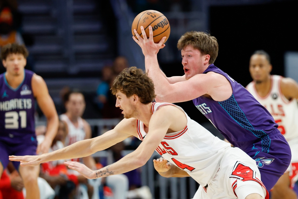 Charlotte Hornets guard Kon Knueppel, right, controls the ball against Chicago Bulls forward Matas Buzelis, left, during the first half of an NBA basketball game in Charlotte, N.C., Friday, Dec. 12, 2025. (AP Photo/Nell Redmond)