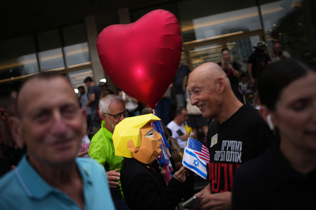 A person wears a mask depicting U.S. President Donald Trump as relatives and supporters of Israeli hostages held by Hamas in the Gaza Strip celebrate following the announcement that Israel and Hamas have agreed to the first phase of a peace plan to pause the fighting, as they gather at a plaza known as hostages square in Tel Aviv, Israel, Thursday, Oct. 9, 2025. (AP Photo/Emilio Morenatti)
