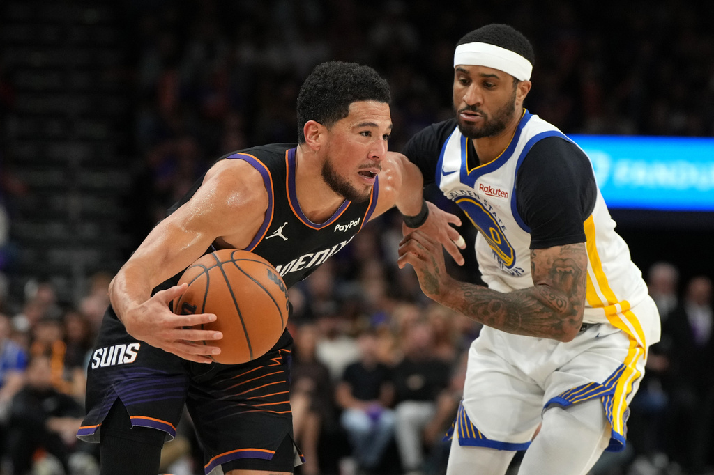 Phoenix Suns guard Devin Booker drives on Golden State Warriors guard Gary Payton II (0) during the second half of an NBA basketball play-in tournament game, Friday, April 17, 2026, in Phoenix. (AP Photo/Rick Scuteri)