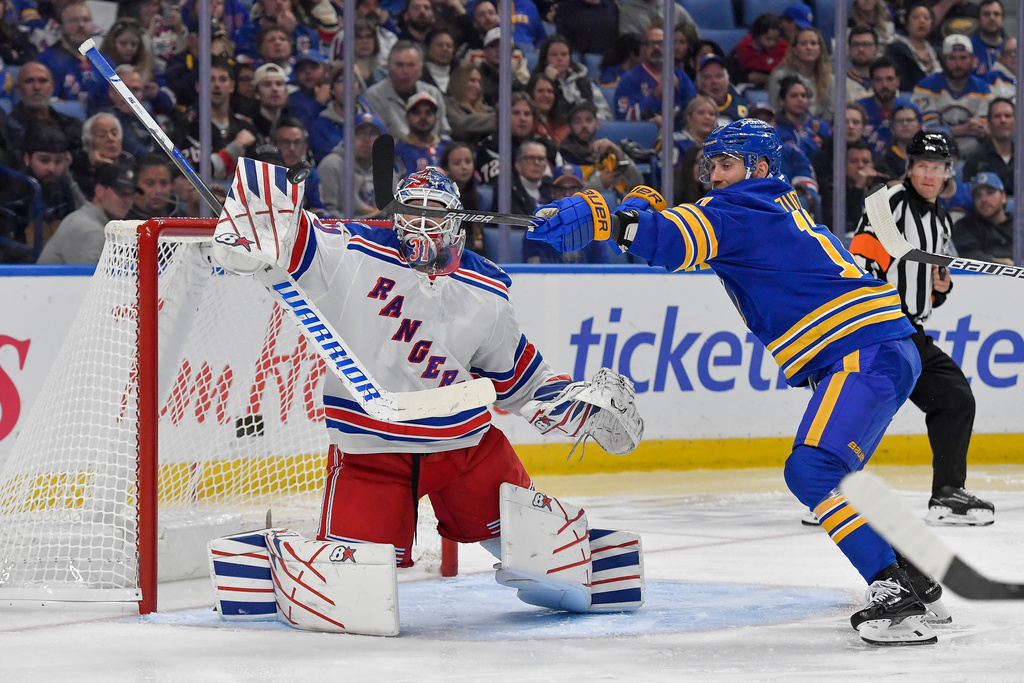 New York Rangers goalie Igor Shesterkin, left, and Buffalo Sabres left wing Jason Zucker reach for the puck during the second period of an NHL hockey game in Buffalo, N.Y., Thursday, Oct. 9, 2025. (AP Photo/Adrian Kraus)